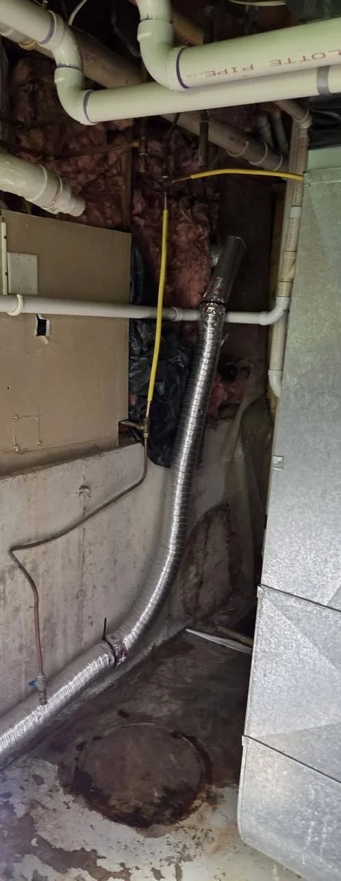 View of a basement or utility room ceiling with various PVC pipes, an HVAC duct, and insulation, along with some electrical wiring.