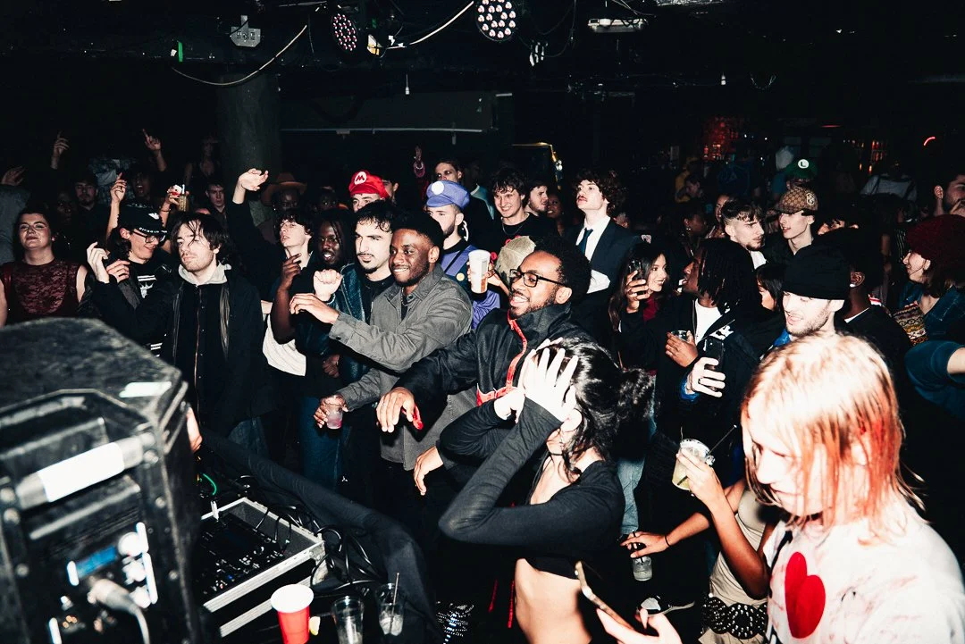 Crowd of diverse people dancing and enjoying music at a nightclub or concert.