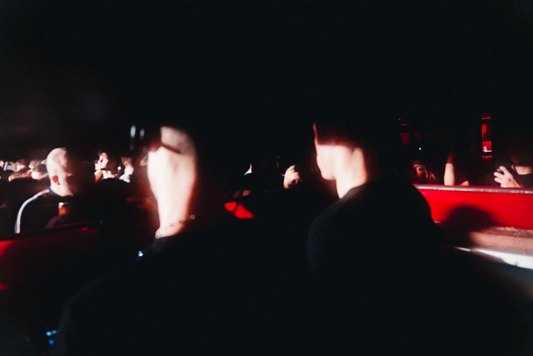 People sitting inside a car at night, with a dark background and red ambient lighting.