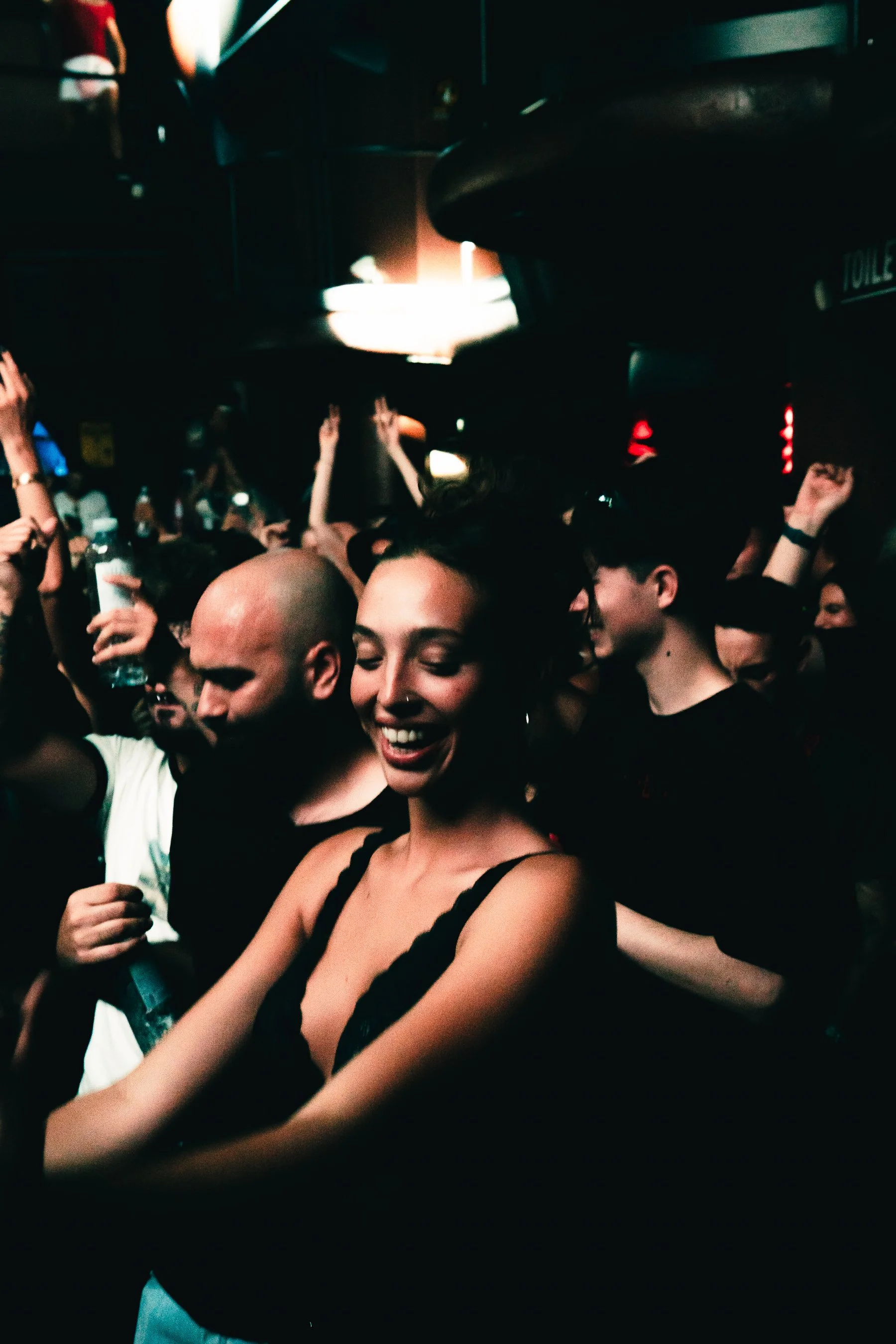 People dancing and enjoying themselves in a dark, crowded nightclub with bright lights and a lively atmosphere.