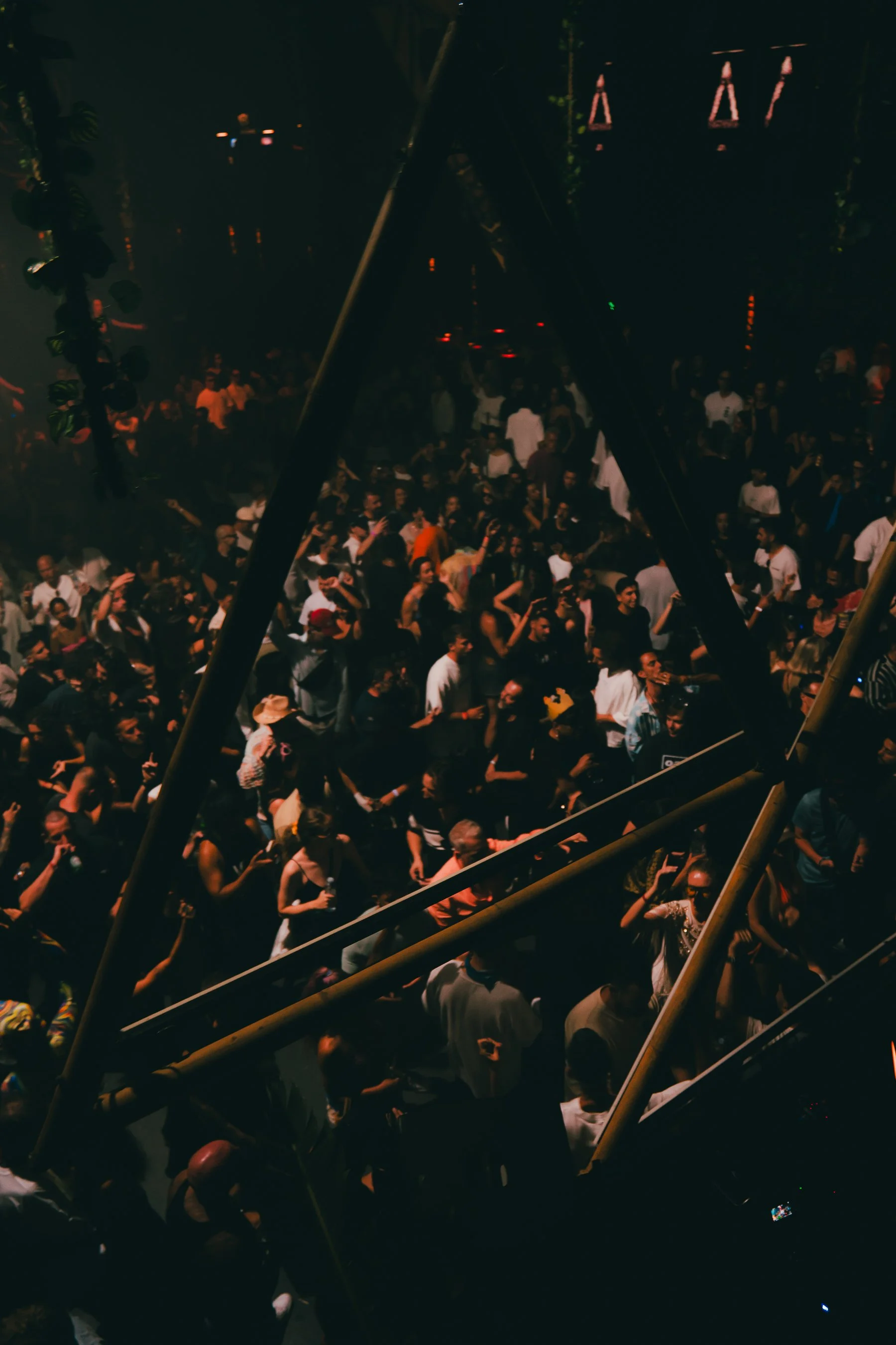A large crowd of people gathered at an outdoor event at night, with some blurred motion and dim lighting.
