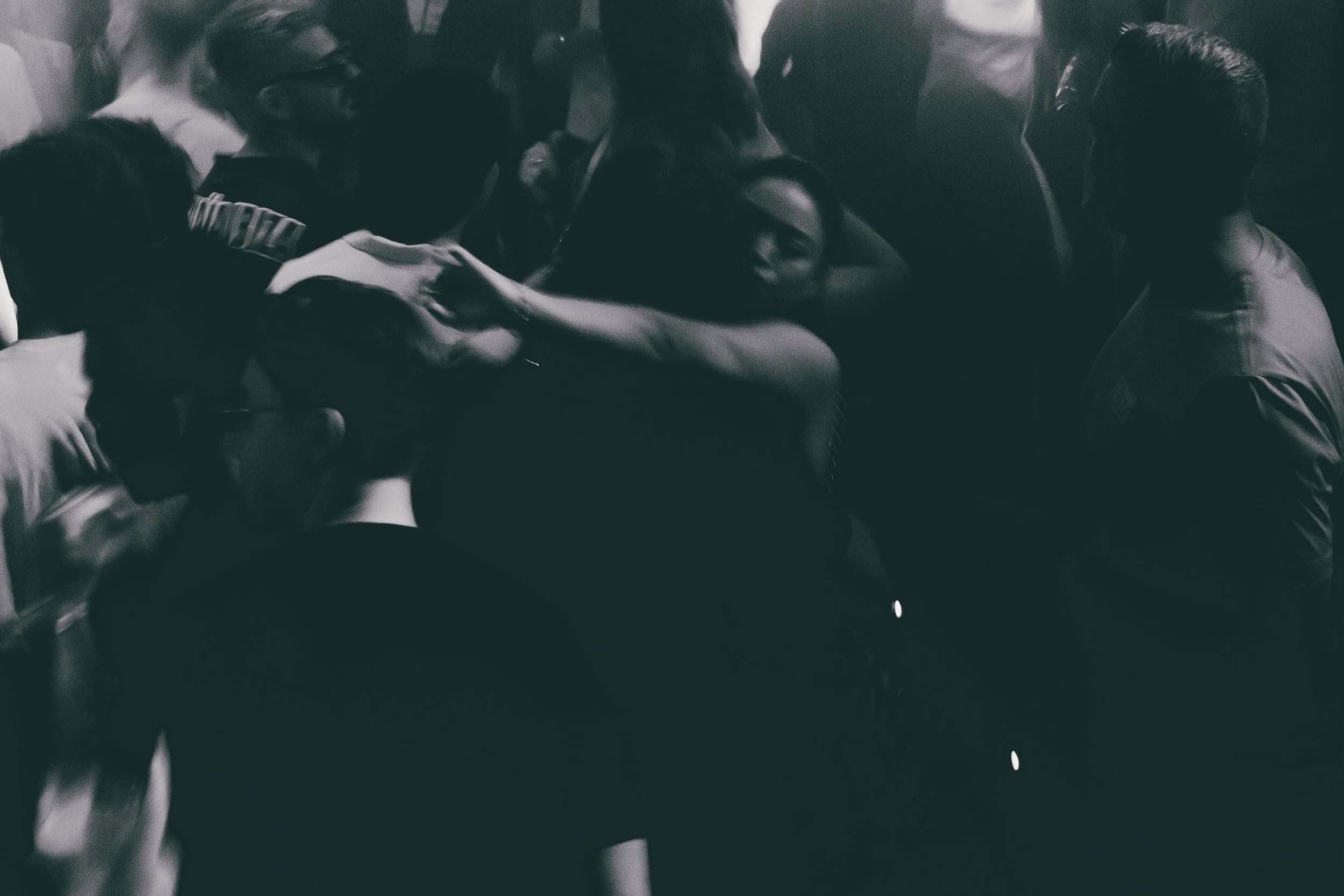 A group of people gathered closely together in a dimly lit setting, seemingly engaged in a shared activity or conversation.