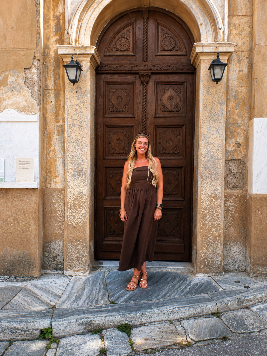 The Olive Branch VA Home page Kelsey standing in a brown dress in front of Ancient Greek doorway