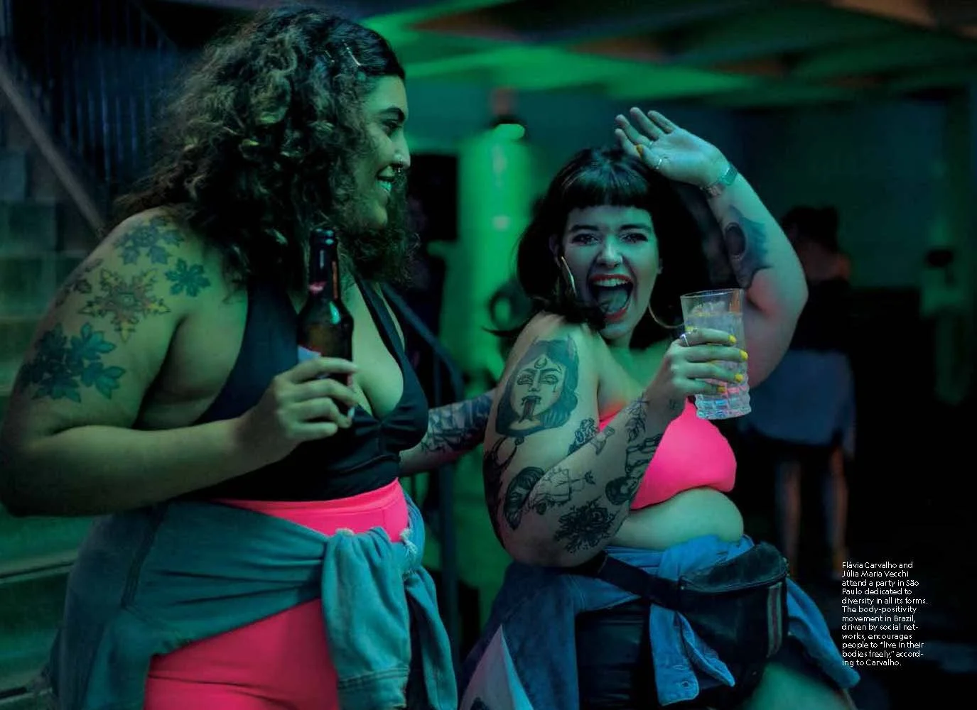 Two women with tattoos dance at a party