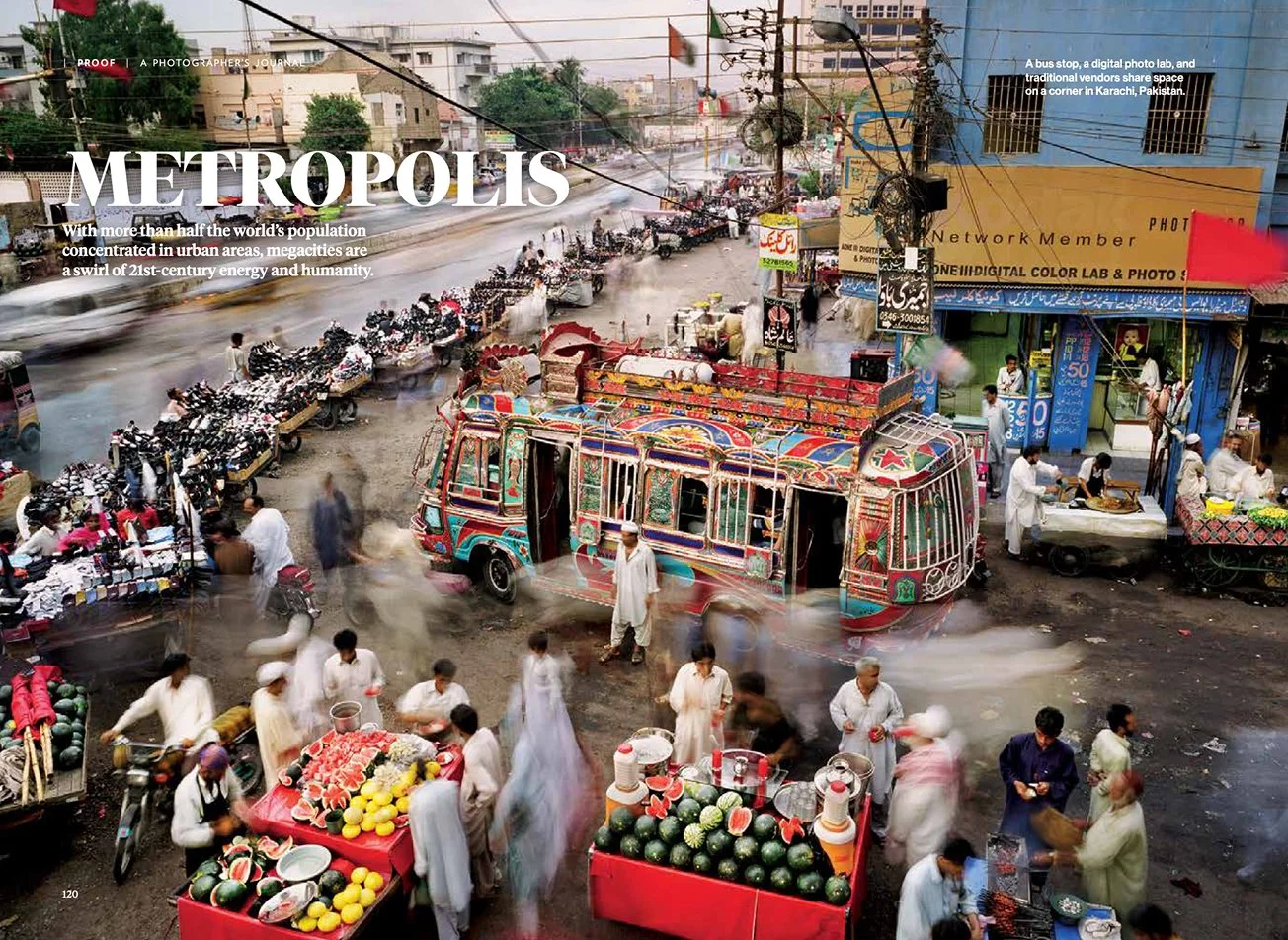 A magazine spread featuring the headline "Metropolis" and an image of a busy street market with vendors selling fruits, a colorful decorated vehicle, and people walking.