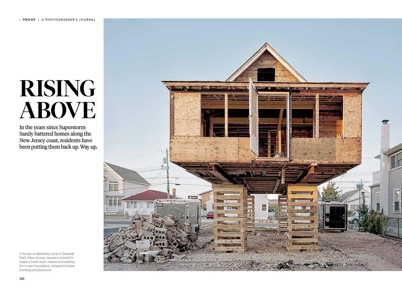 A magazine spread featuring the headline "Rising Above" and a photograph of an under construction house on stilts in a neighborhood, with a pile of bricks and construction equipment nearby.