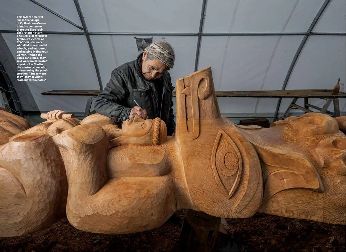 A person carving a large wooden sculpture inside a workshop.