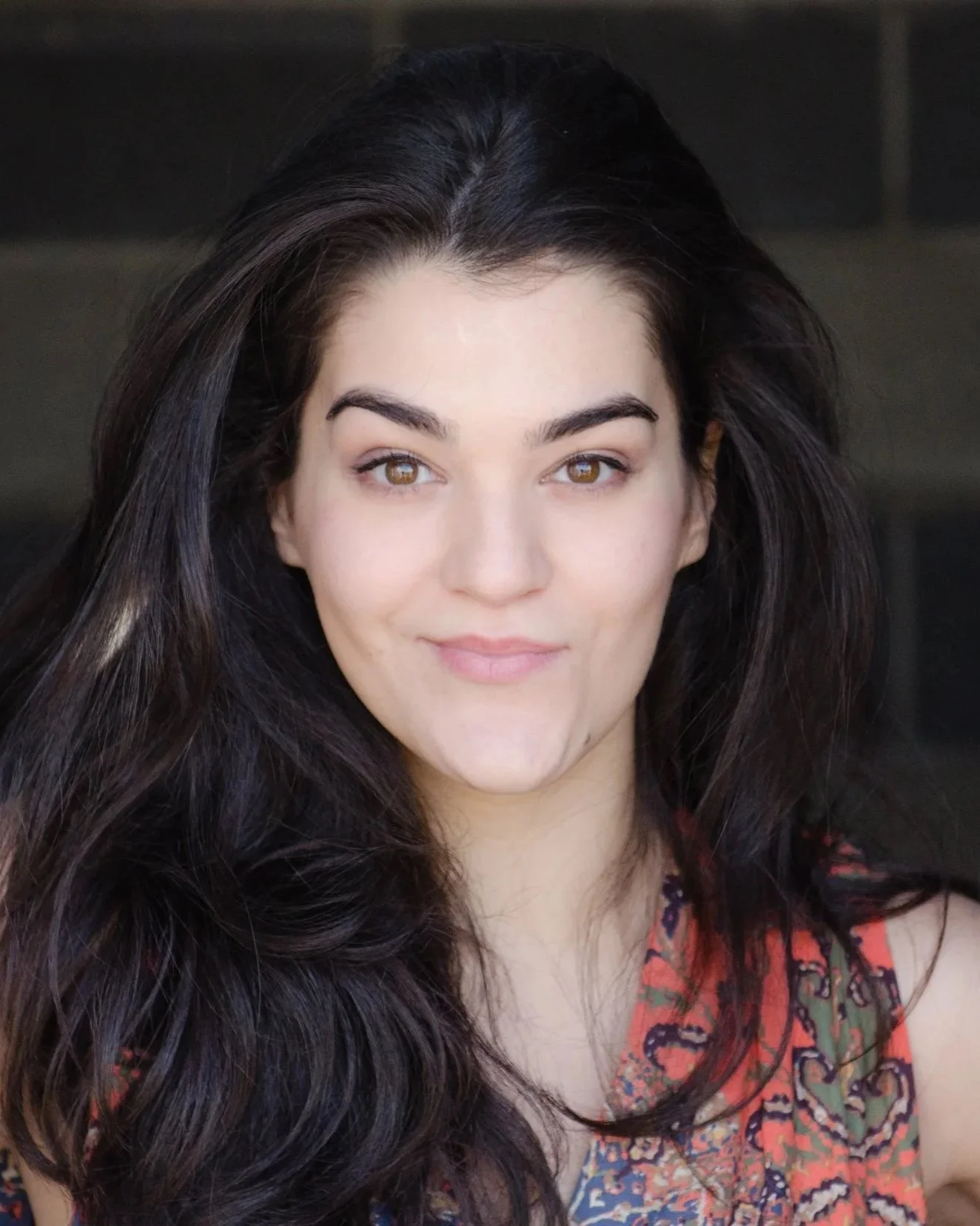 Close-up of a Lauren Ezzo with long dark hair, light skin, and brown eyes, wearing a colorful patterned top.