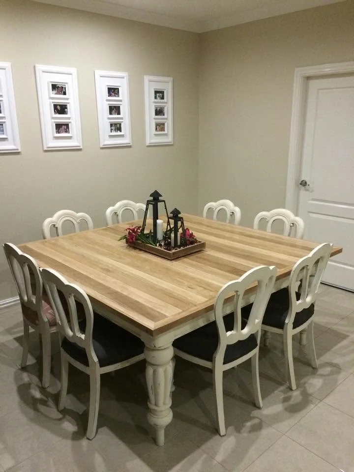 A dining room table with eight chairs, a decorative lantern centerpiece, and framed photos on the wall.