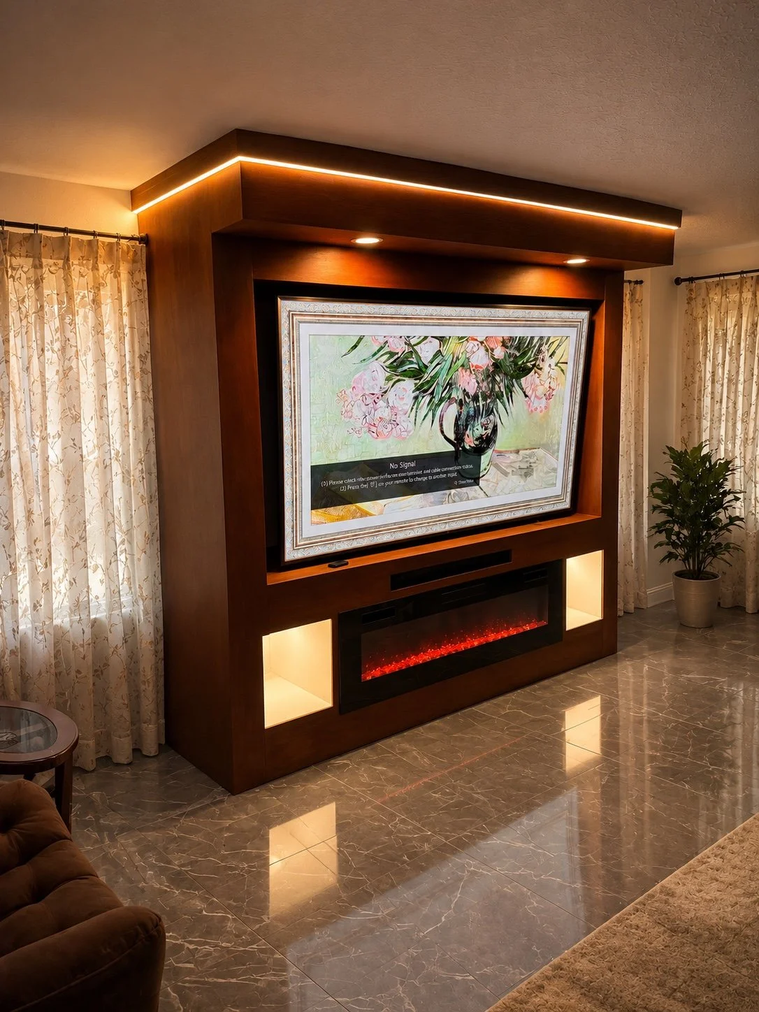 Living room with a flat-screen TV displaying a floral painting, mounted in a wooden entertainment center with built-in lighting and electric fireplace, beige curtains, and potted plant.
