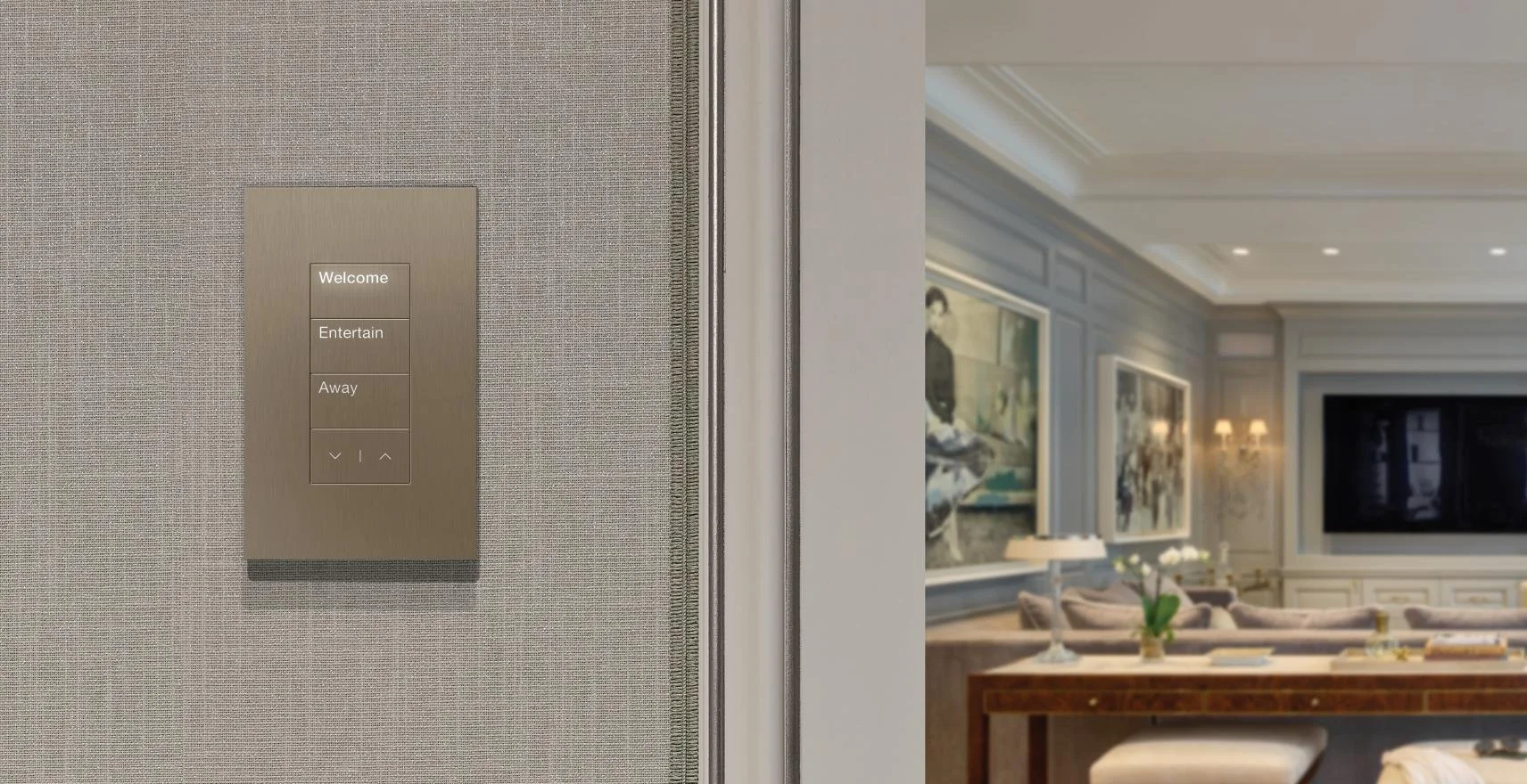 Elevator control panel with buttons labeled Welcome, Entertain, Away, down arrow, and up arrow, situated on a beige textured wall in a luxurious living room with paintings, a large TV, lamps, a couch, and decorative plants.