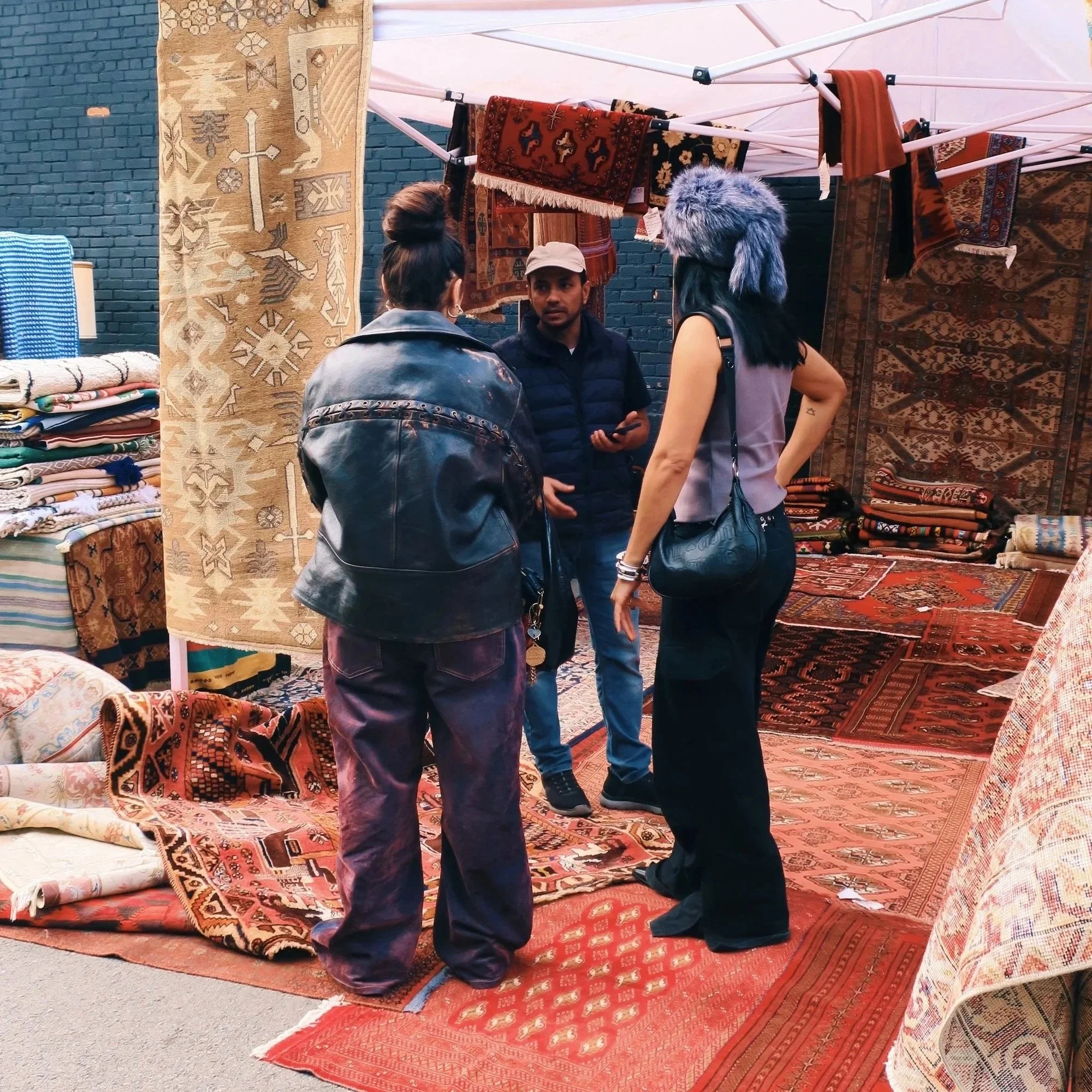 Abdul shows his beautiful rugs to a couple of fashionable patrons