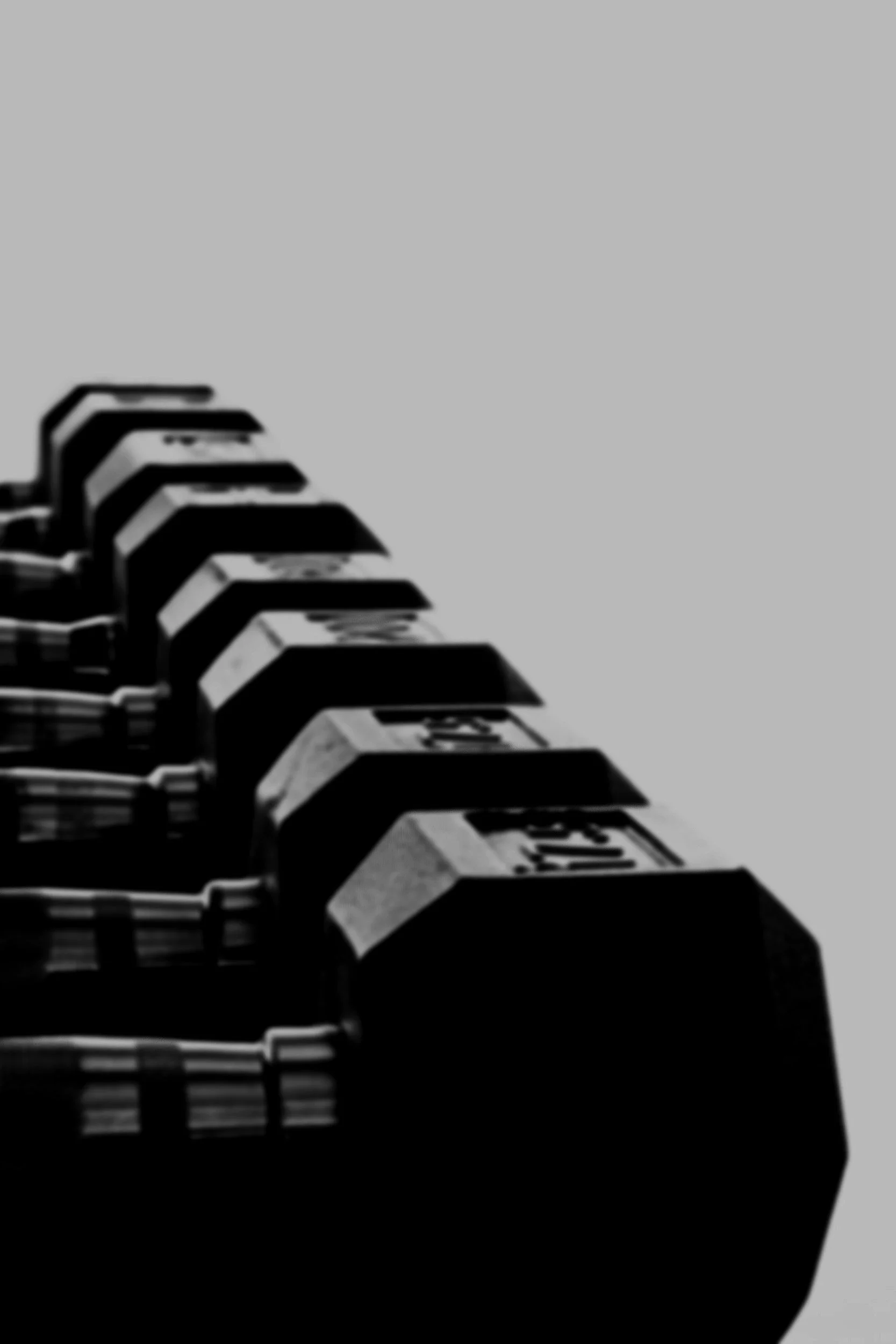 Close-up of black and white gym dumbbells with a gray background.