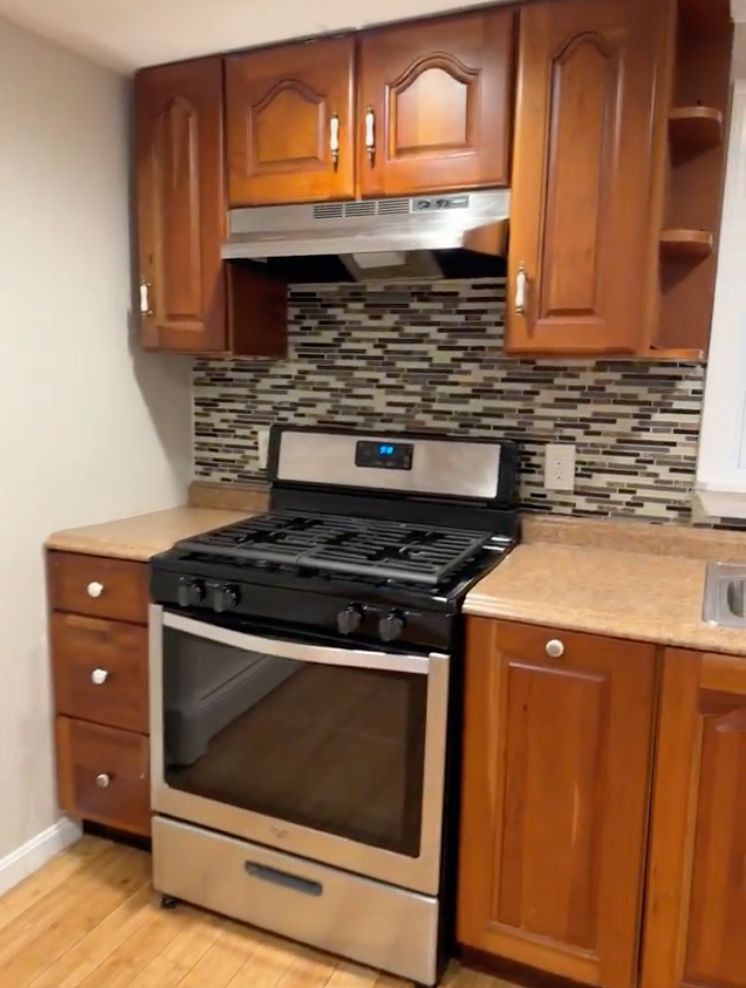 Clean and organized kitchen with stove and cabinets after a standard residential cleaning.