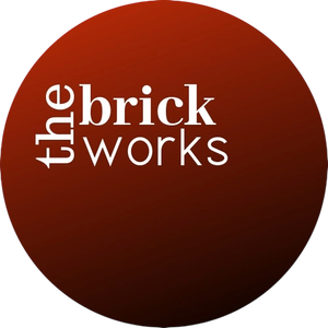 A circular logo with a dark red gradient background and the text 'the brick works' arranged vertically and horizontally in white.