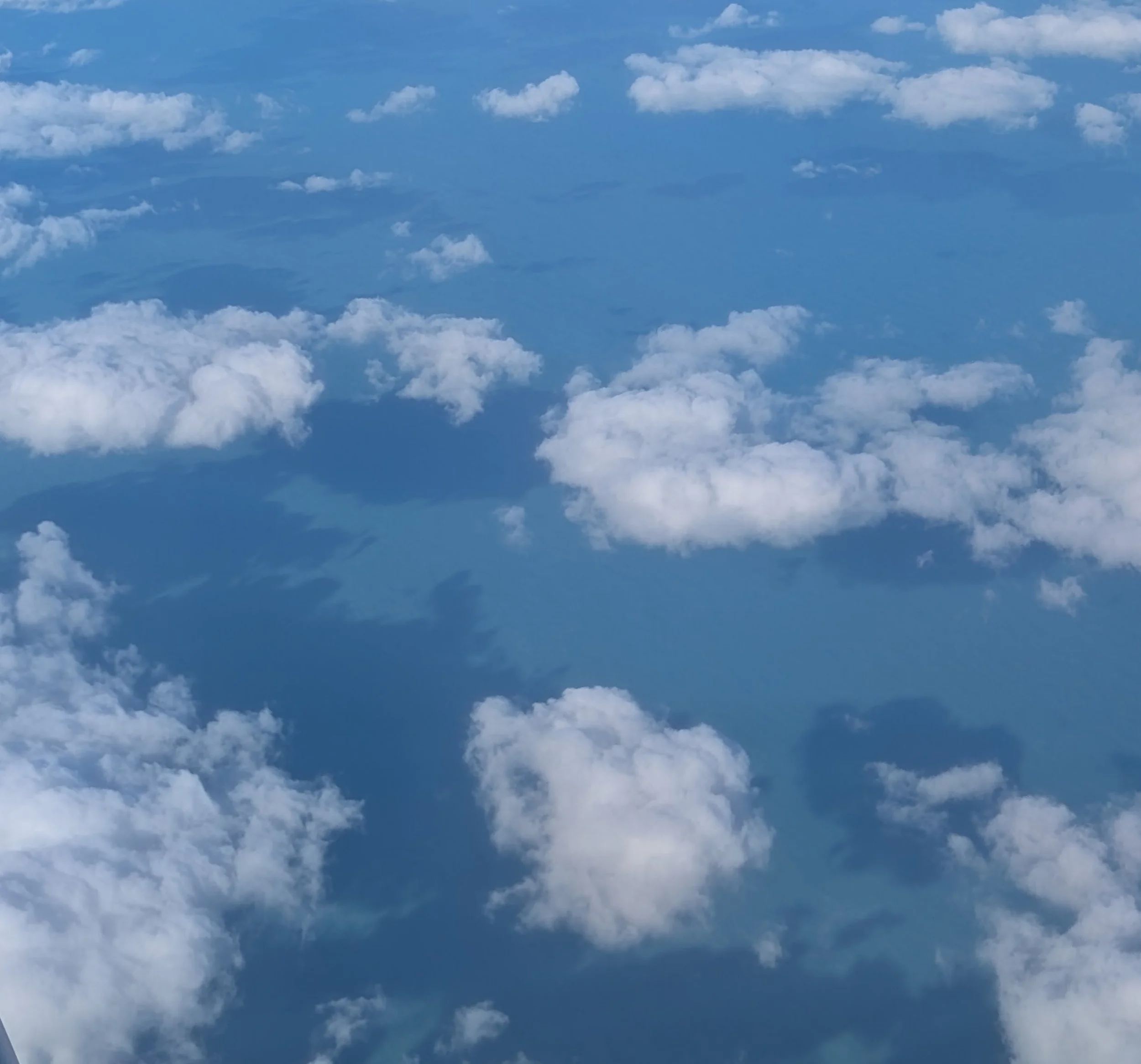 A bright blue sky filled with numerous fluffy white clouds scattered across the scene.
