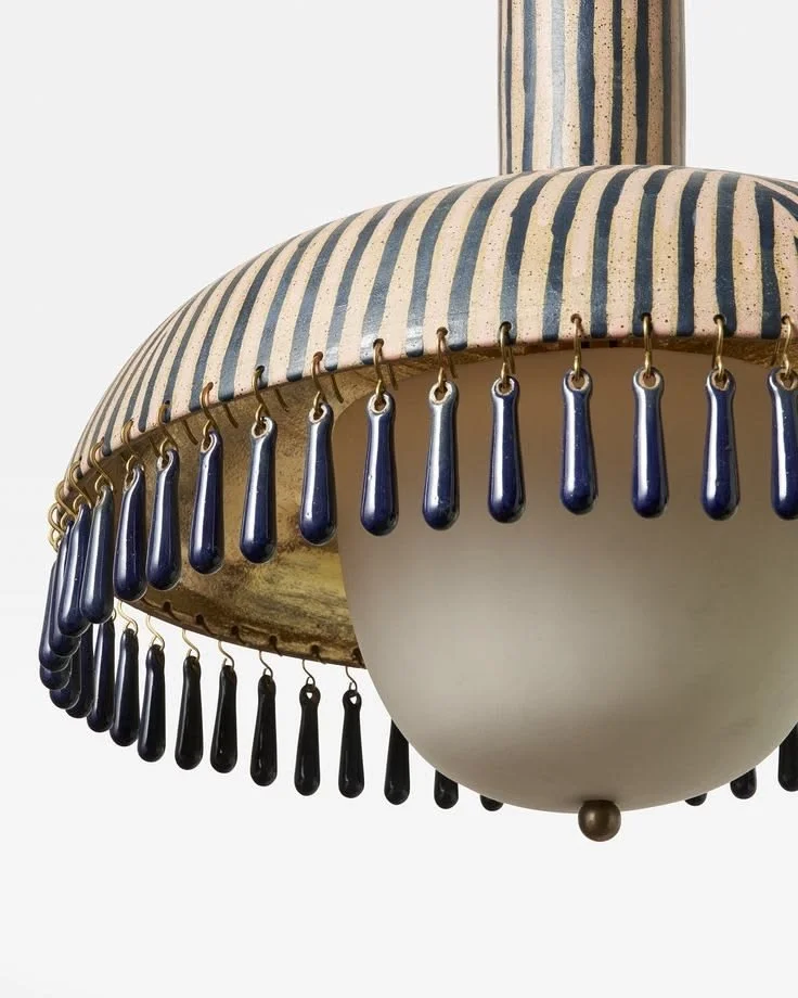 Close-up of a ceiling lamp with blue and black beads hanging from a striped fabric lampshade.