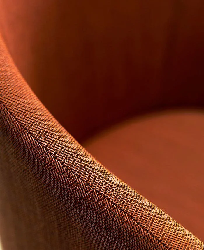 Close-up of a fabric-covered chair with reddish-brown textured upholstery.