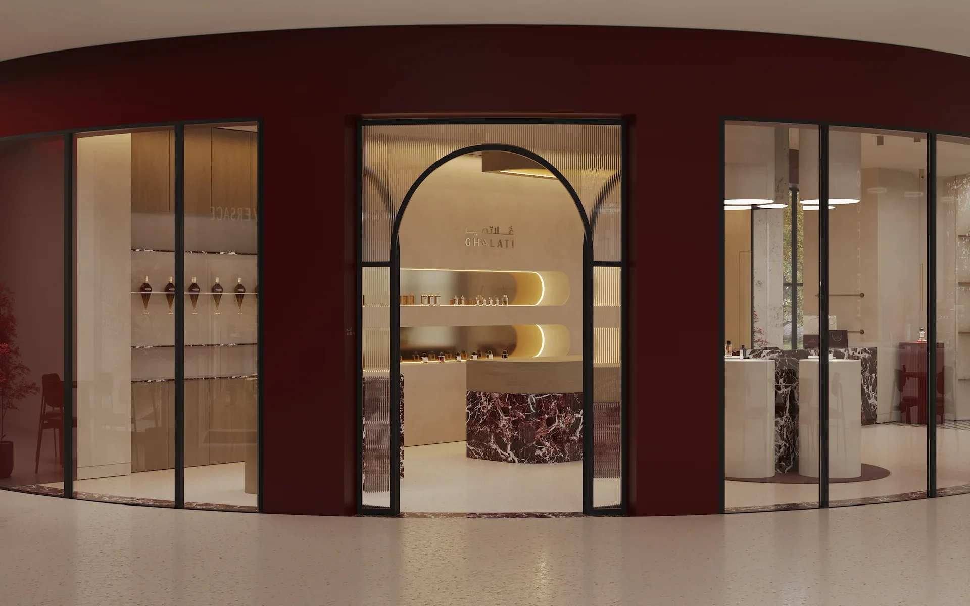 Modern retail or showroom storefront with curved glass panels, red exterior walls, and a sleek interior display area featuring shelves with bottles, and a reception area with a marble counter and warm lighting.