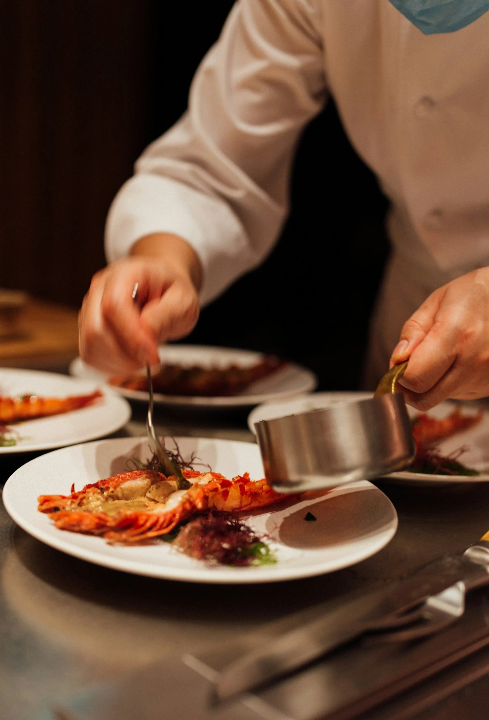 A chef preparing lobster dishes at a restaurant kitchen.