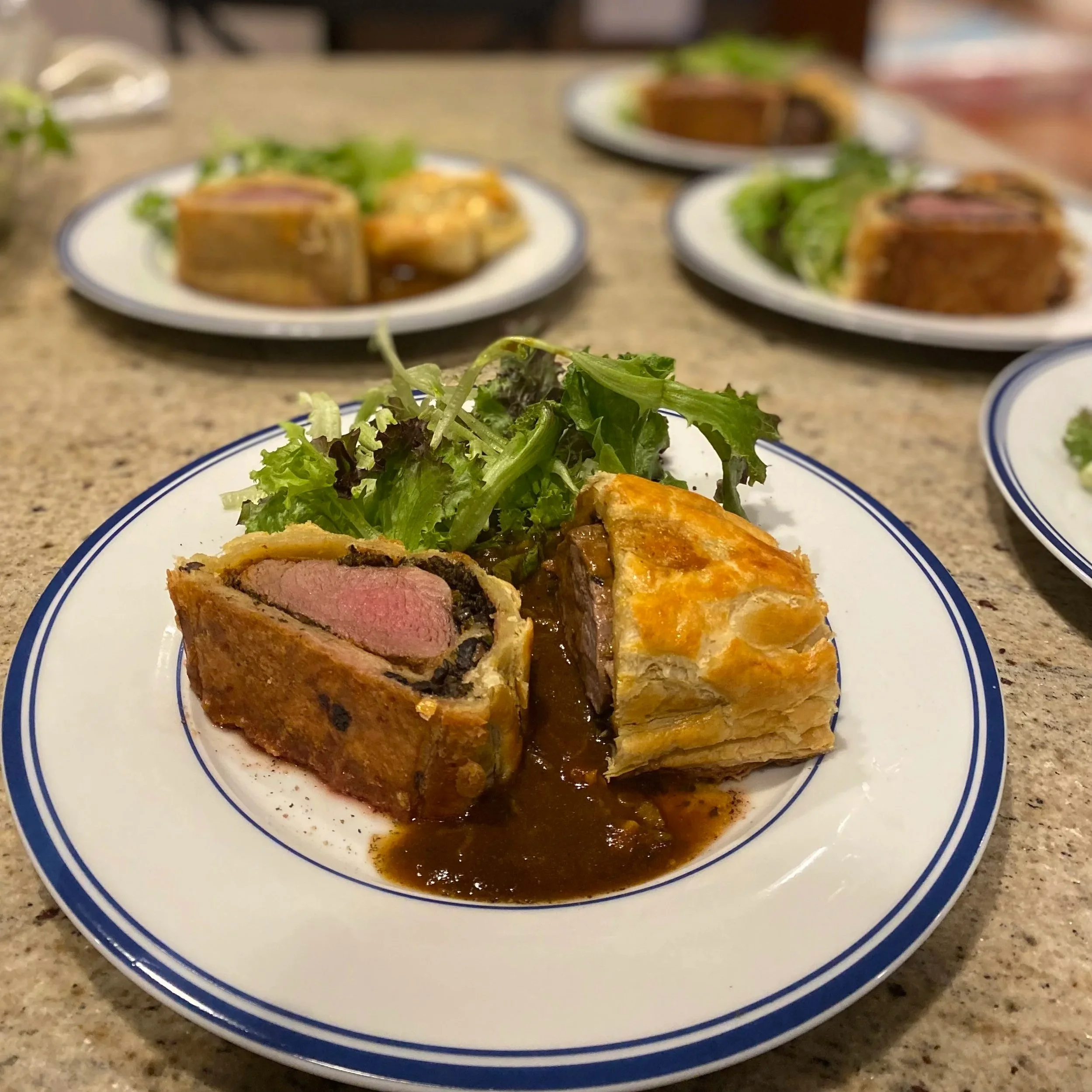 A plate of cooked beef Wellington with a side of green salad.