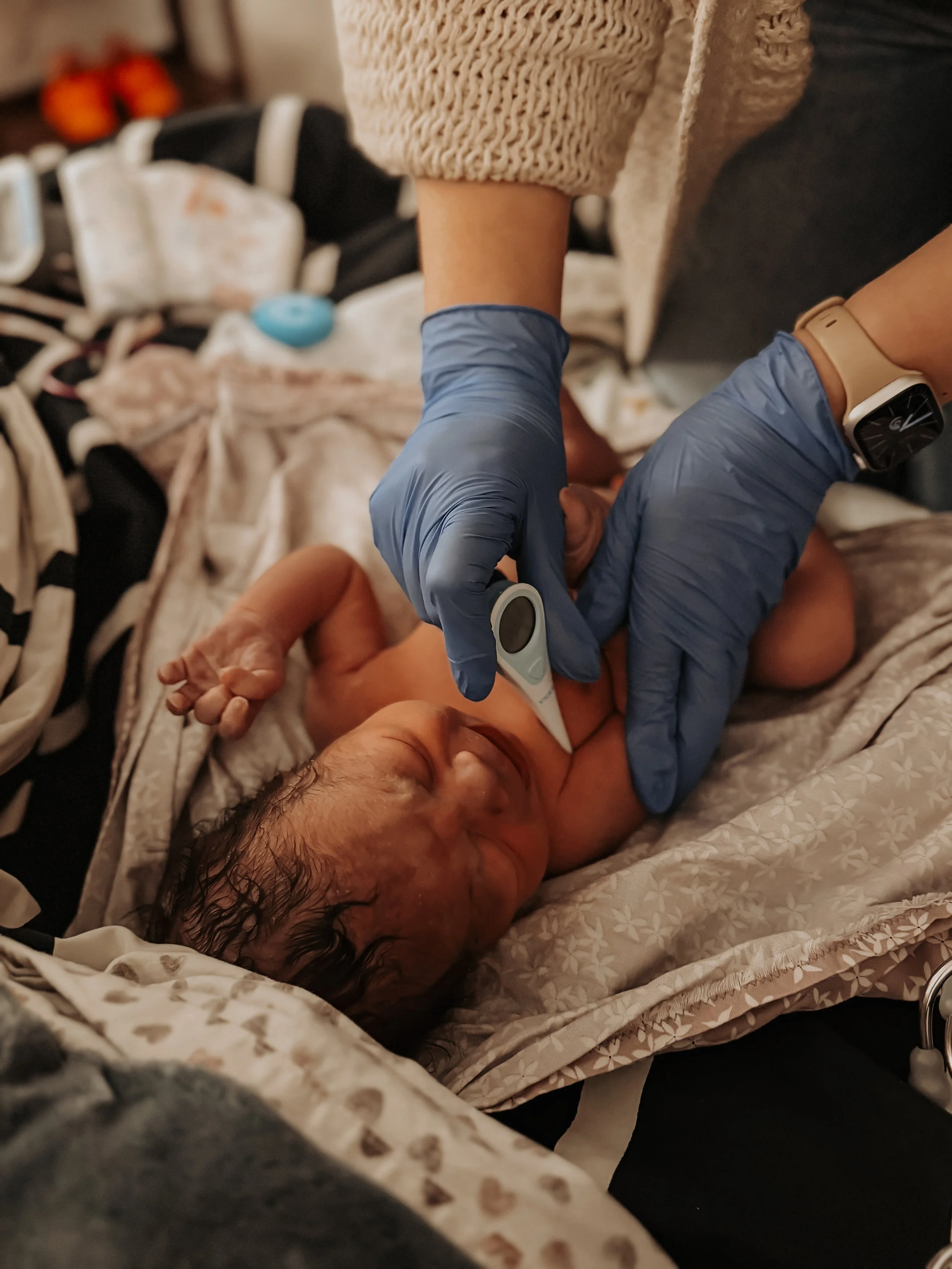 An elderly man lying in bed, receiving a medical check-up with a thermometer, while a healthcare worker wearing blue gloves checks his temperature.