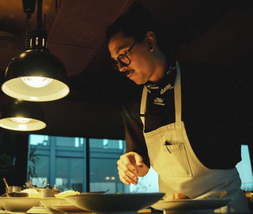 Chef en una cocina, preparando alimentos en un ambiente con iluminación cálida y moderna. Charco, Ricardo Verdejo, Centro, CDMX.