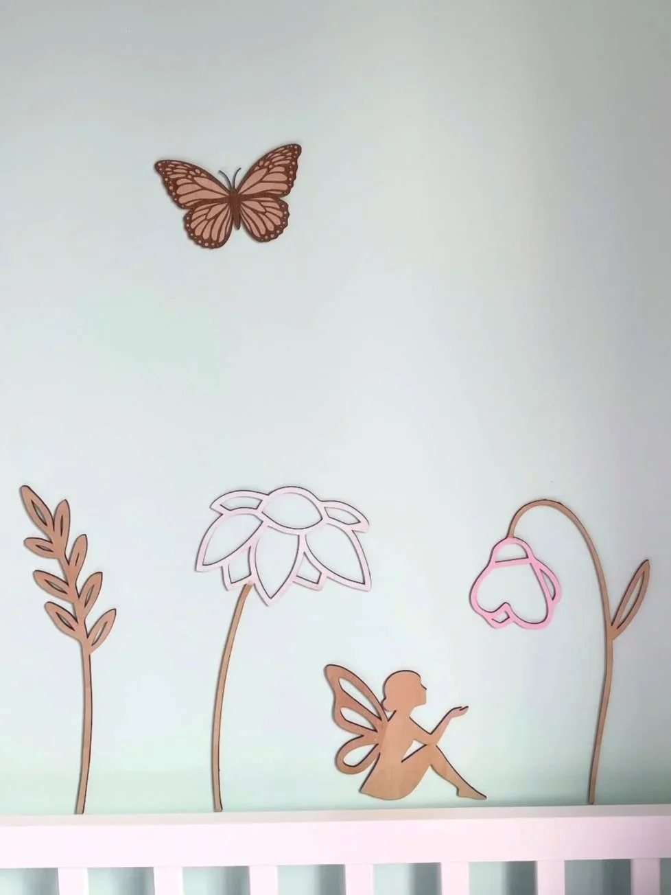 Decorative wall with a butterfly, a fairy, flowers, and a fairy sitting on the ground.