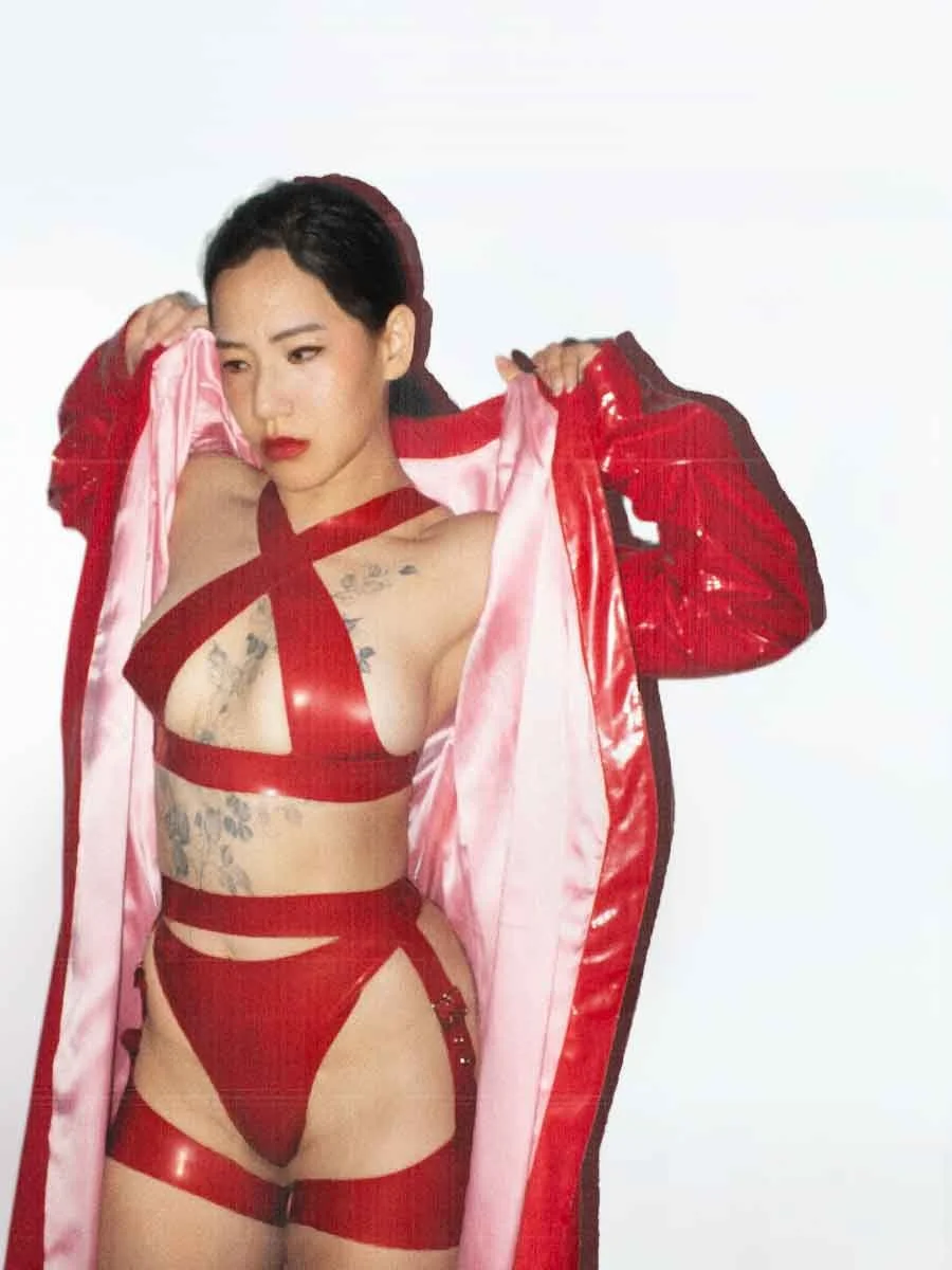 Mizu, NYC dominatrix, Fit, in red latex harness lingerie, shedding pink satin-lined robe — editorial portrait