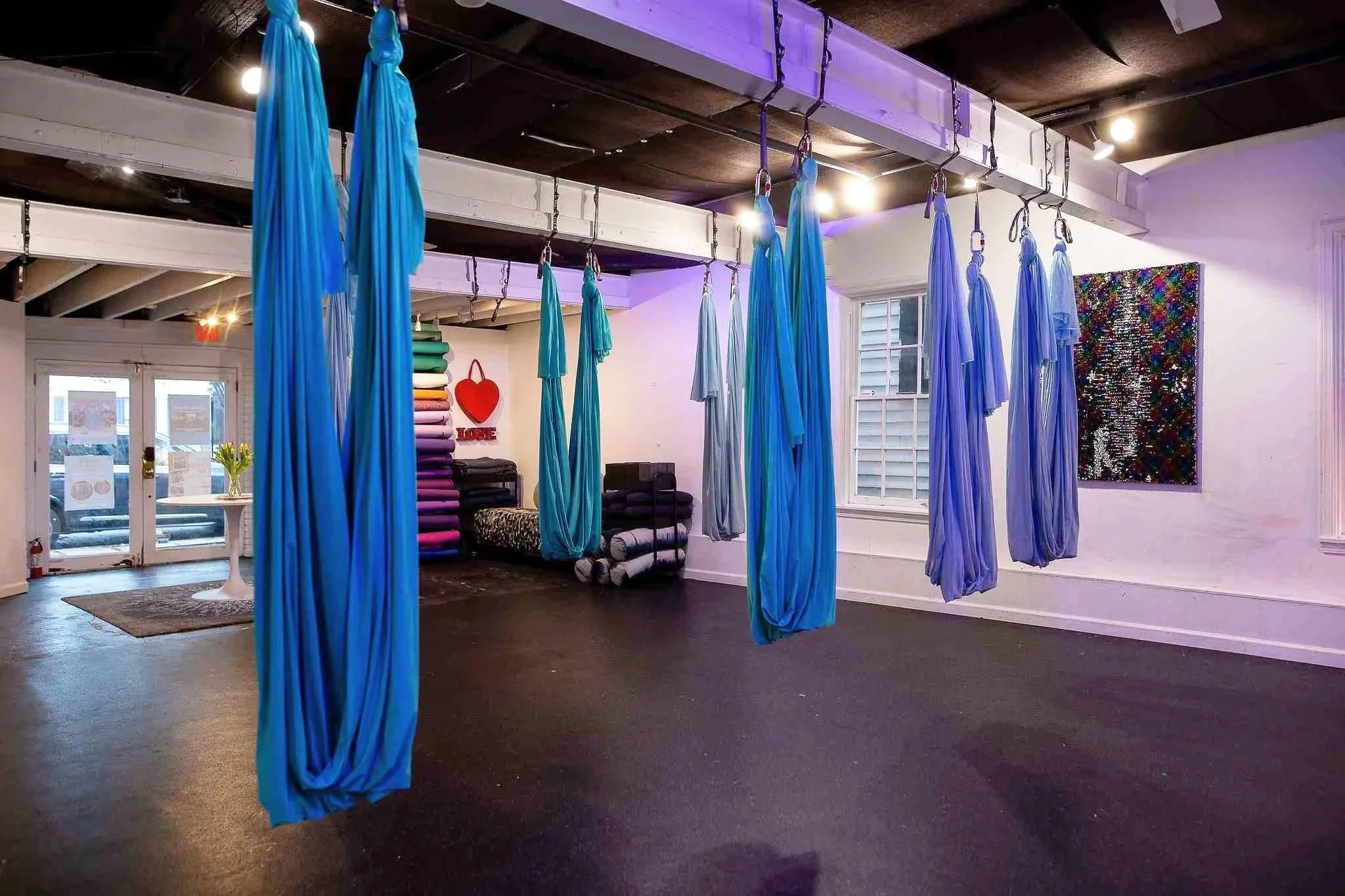Indoor space with blue aerial silk fabric hangings suspended from the ceiling.
