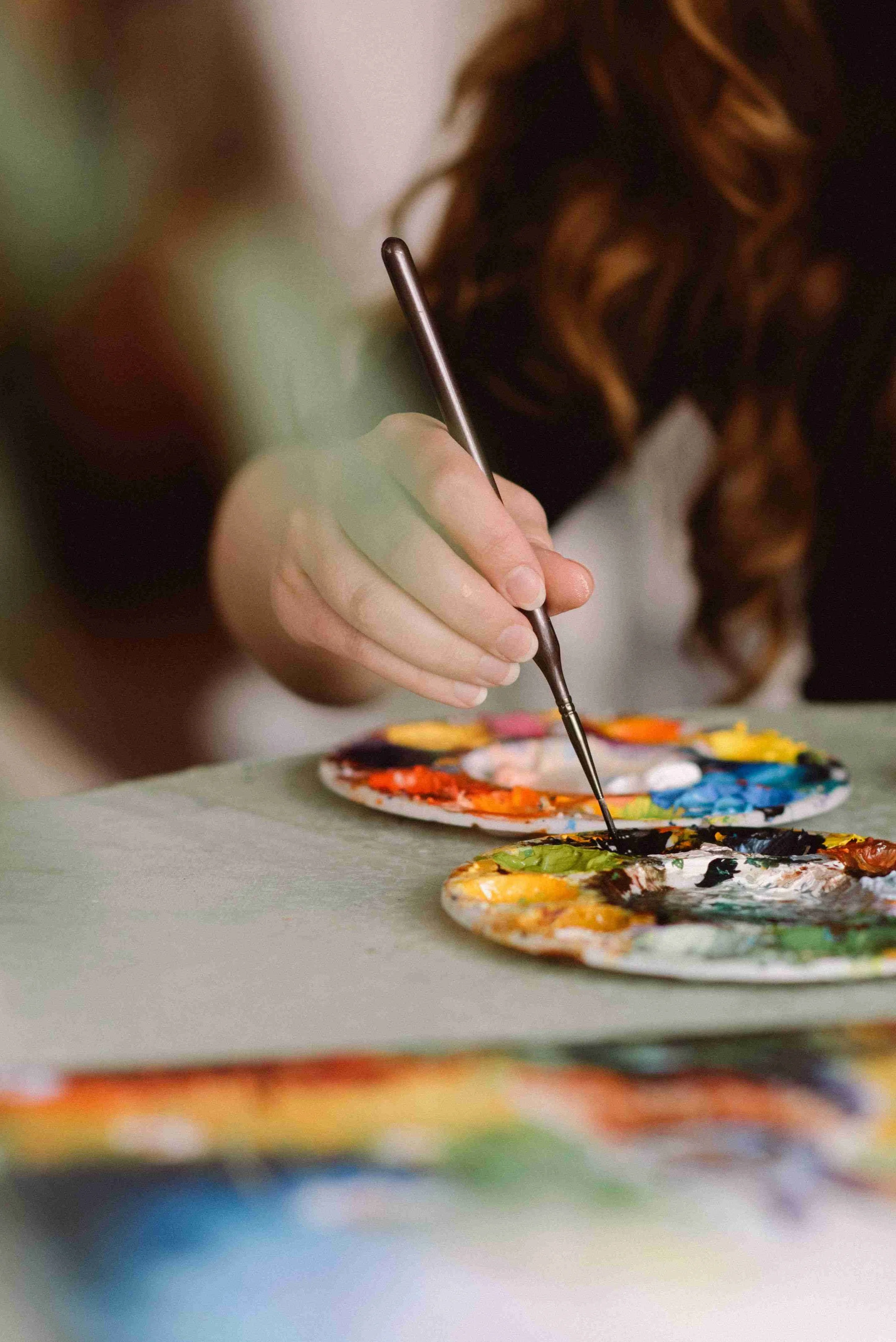 A person painting on a palette with watercolor paints.