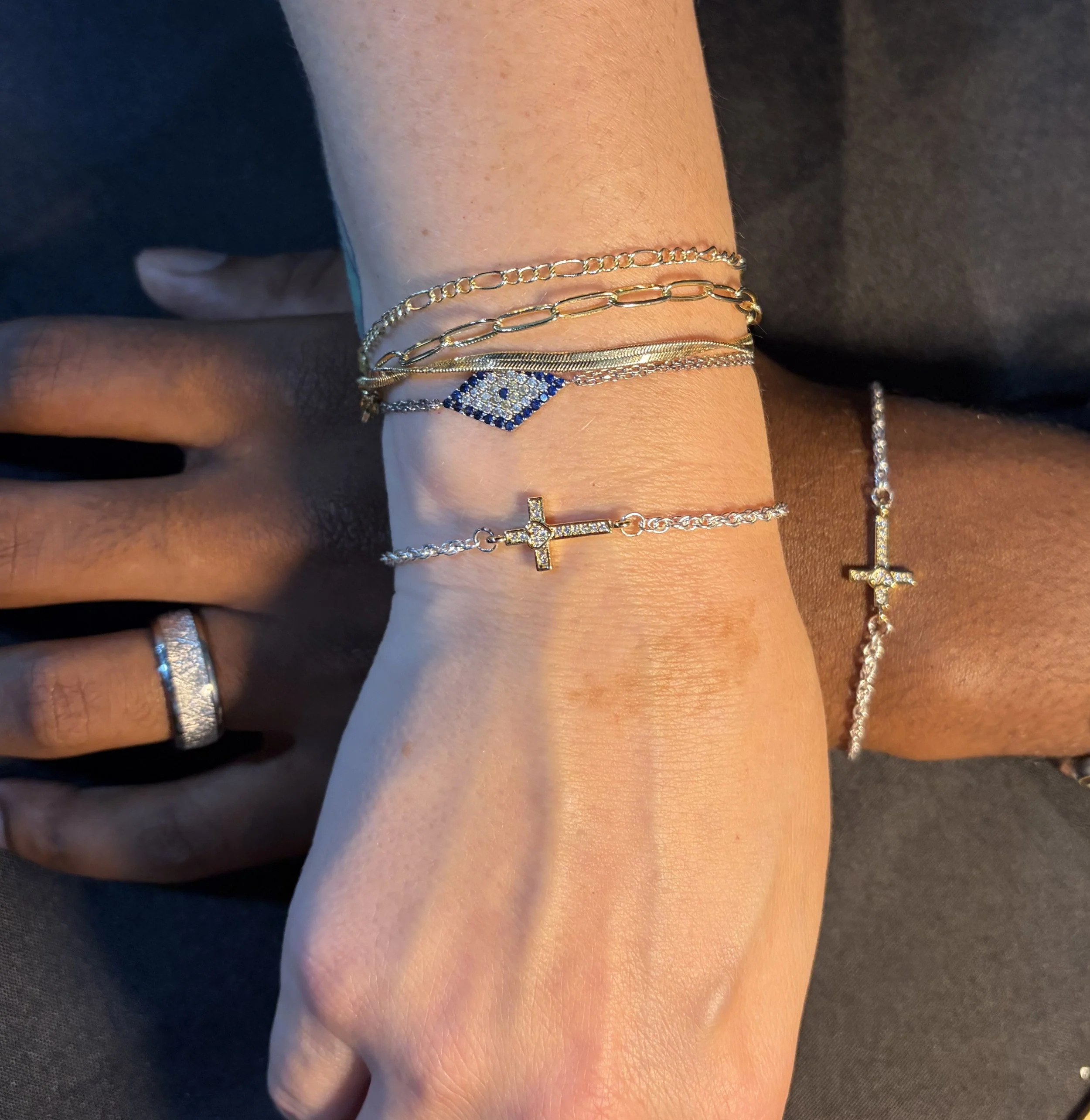 Multiple gold and silver bracelets worn on a person's wrist, with a black or dark gray background.