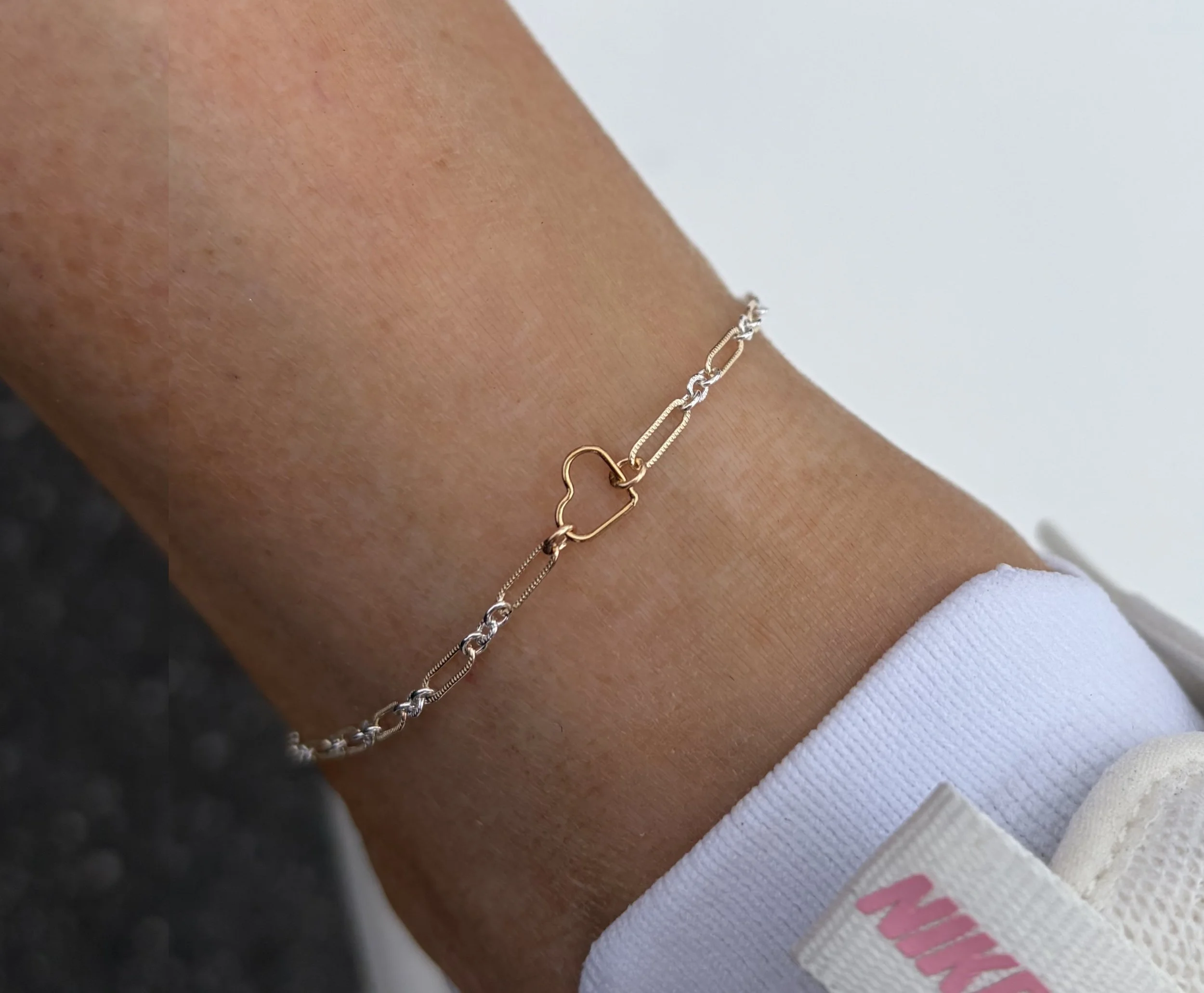 Close-up of a person's arm wearing two delicate gold and silver chain bracelets.