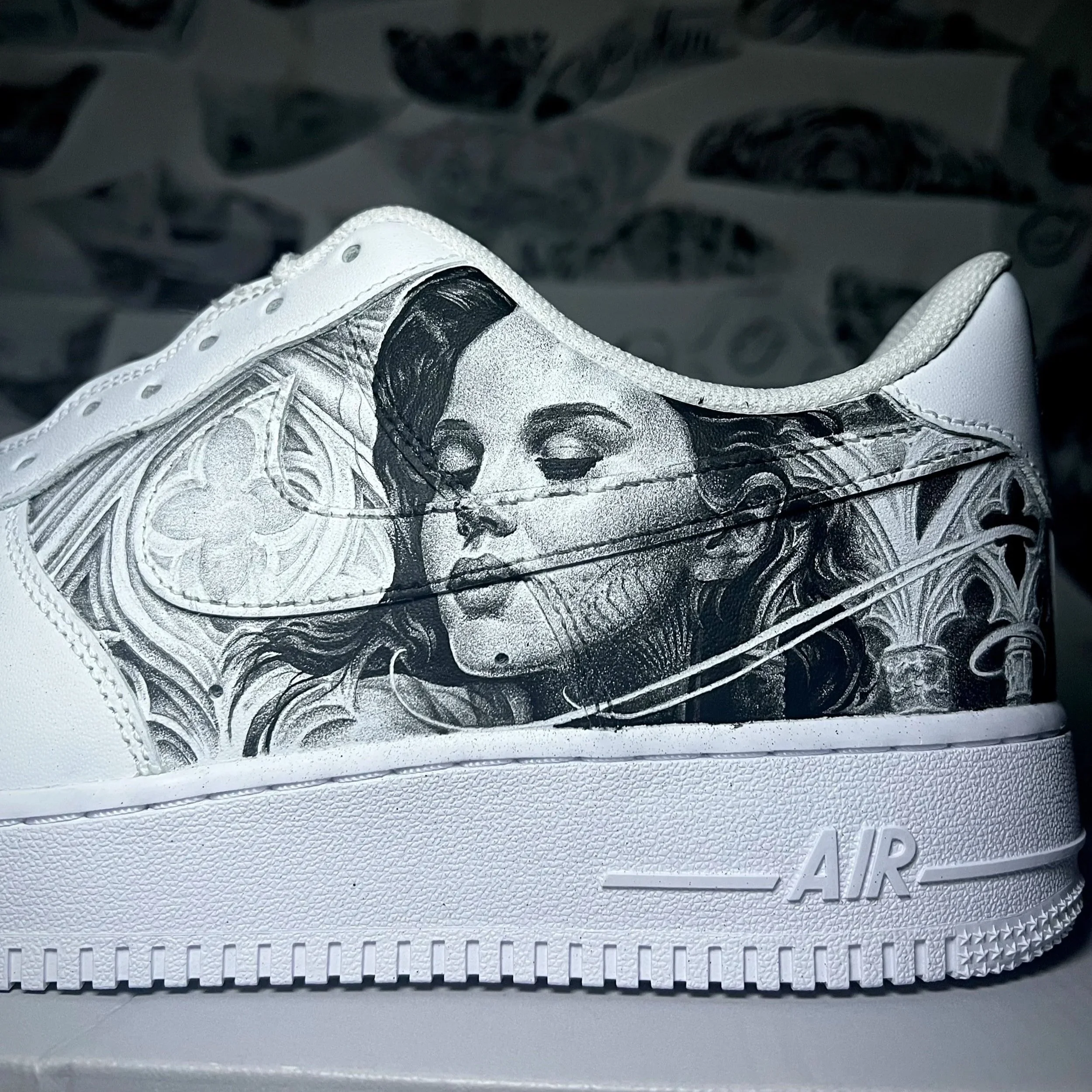 Close-up of a white sneaker with black and silver accents, placed on a textured white surface.
