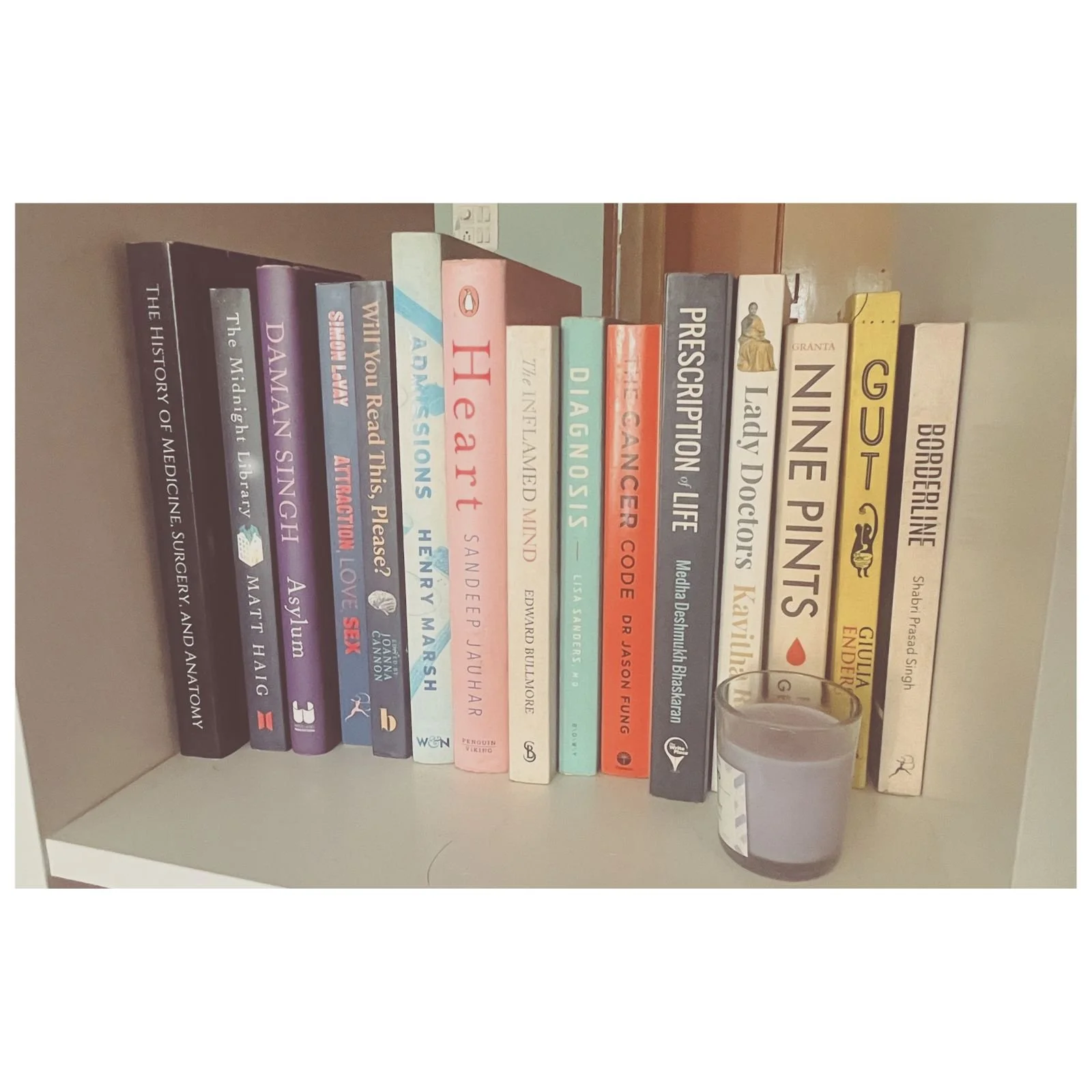 Bookshelf with books about medicine, history, and personal development, and a glass of purple drink in front.