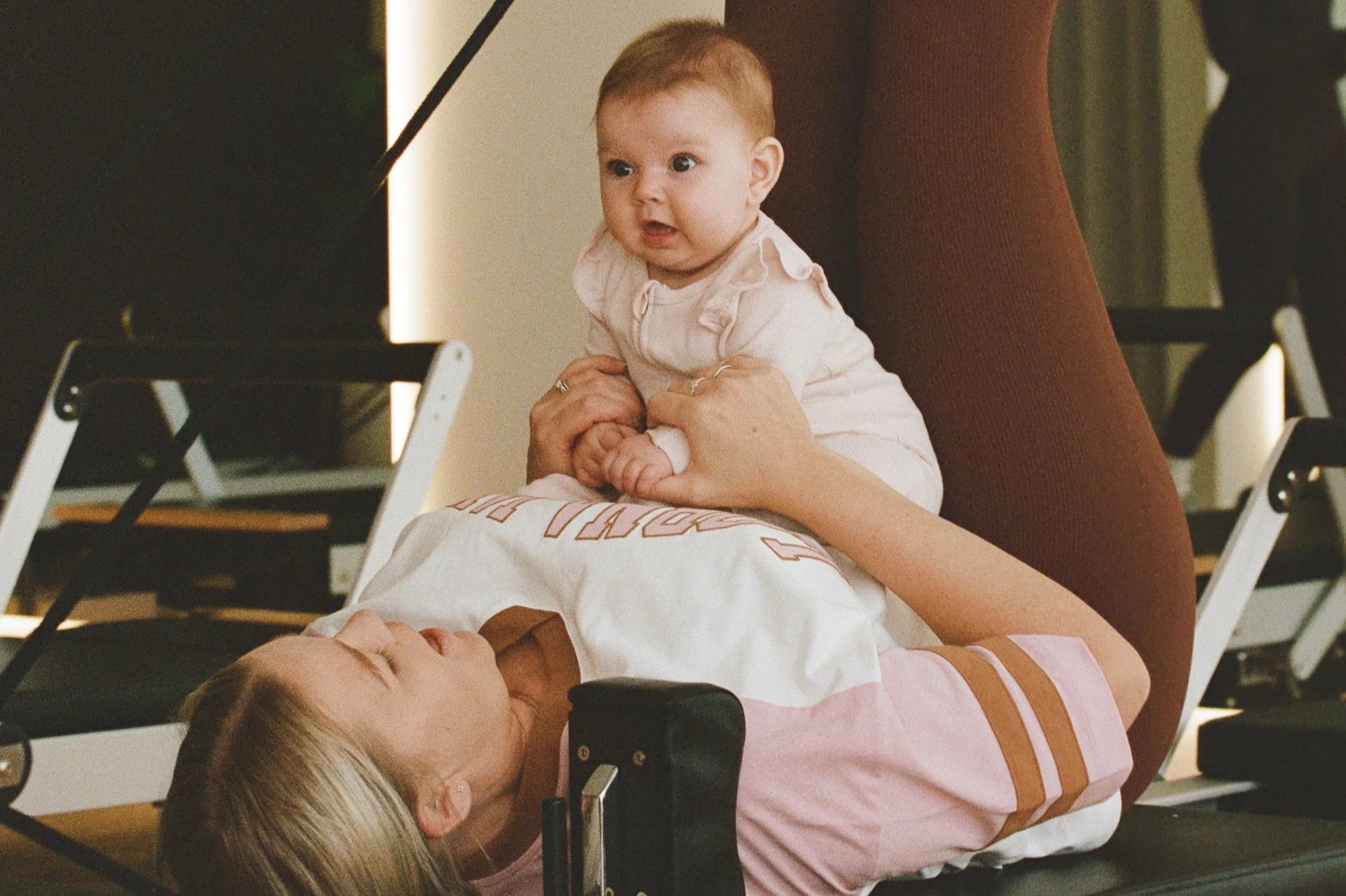 Baby sitting on an adult's lap on a pilates reformer