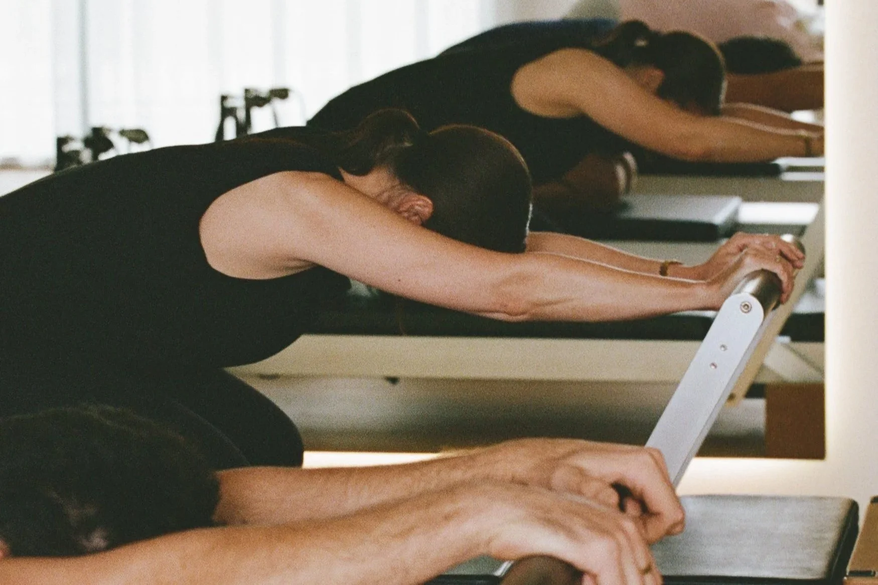 People practicing Pilates on reformer machines in a studio