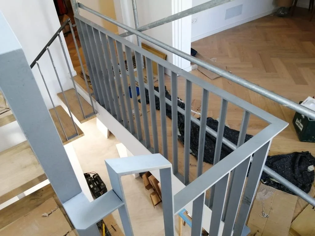 Barandilla de metal en proceso de instalación en una escalera interna de una casa.
