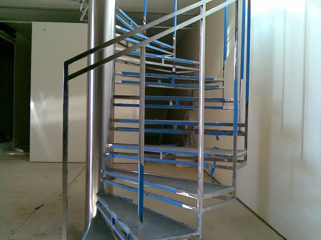Escalera de caracol metálica en construcción, parte de un interior en obra.