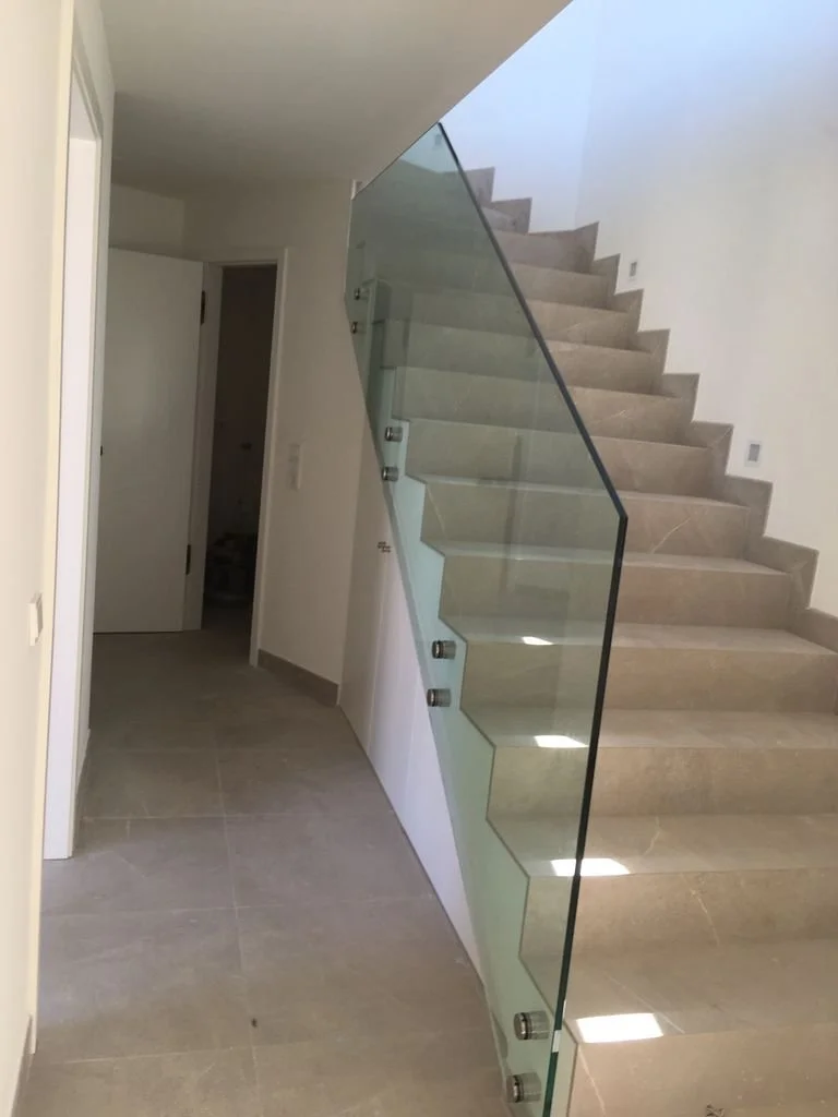 Escalera interior de moda moderna con mampara de vidrio y peldaños de piedra en un ambiente minimalista y elegante.