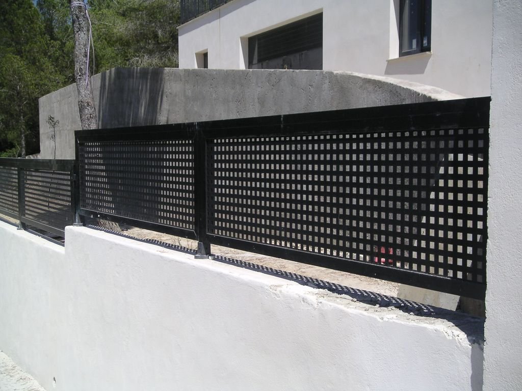 Valla negra con diseño de cuadrícula en el frente de una propiedad moderna.
