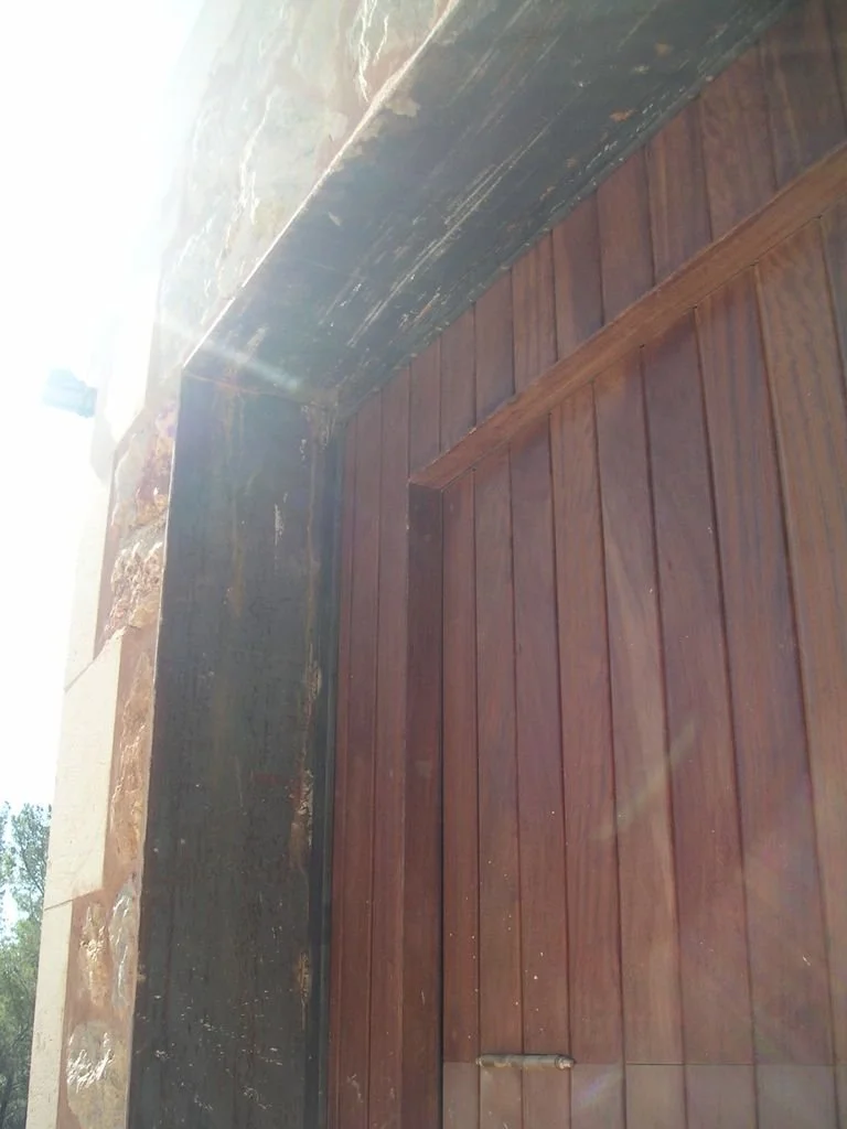 Puerta de madera cerrada en una estructura con paredes de piedra.