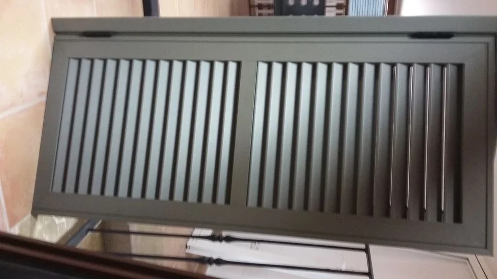 Puerta de madera pintada de gris con barras verticales, en un entorno interior.