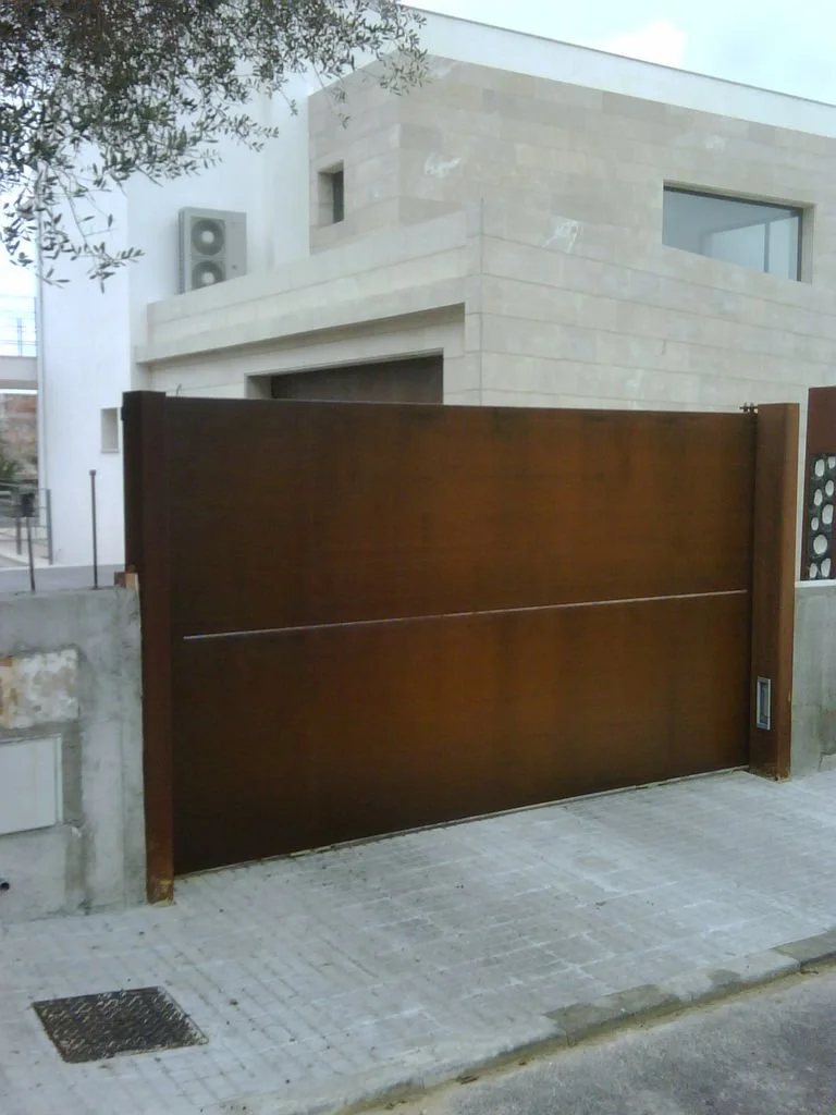 Puerta automátic para garaje en una casa moderna con muro de piedra y ventanas grandes.