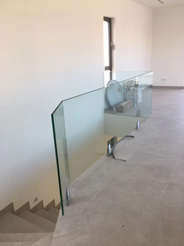 Vidrio de protección en una escalera interior, con una ventana al fondo, en un espacio vacío de construcción o renovación.