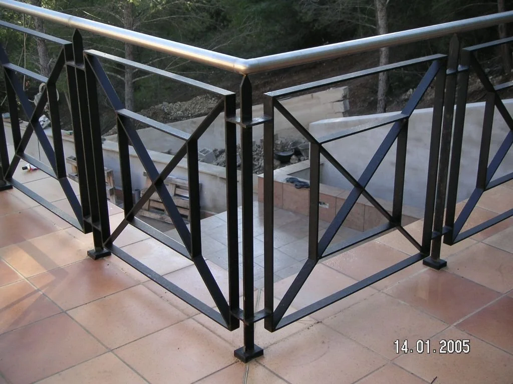 Barandal de metal negro con barandilla de acero inoxidable en balcón de azulejo en una terraza exterior