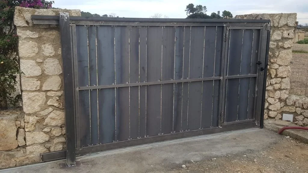 Puerta metálica negra con cerradura en una pared de piedra