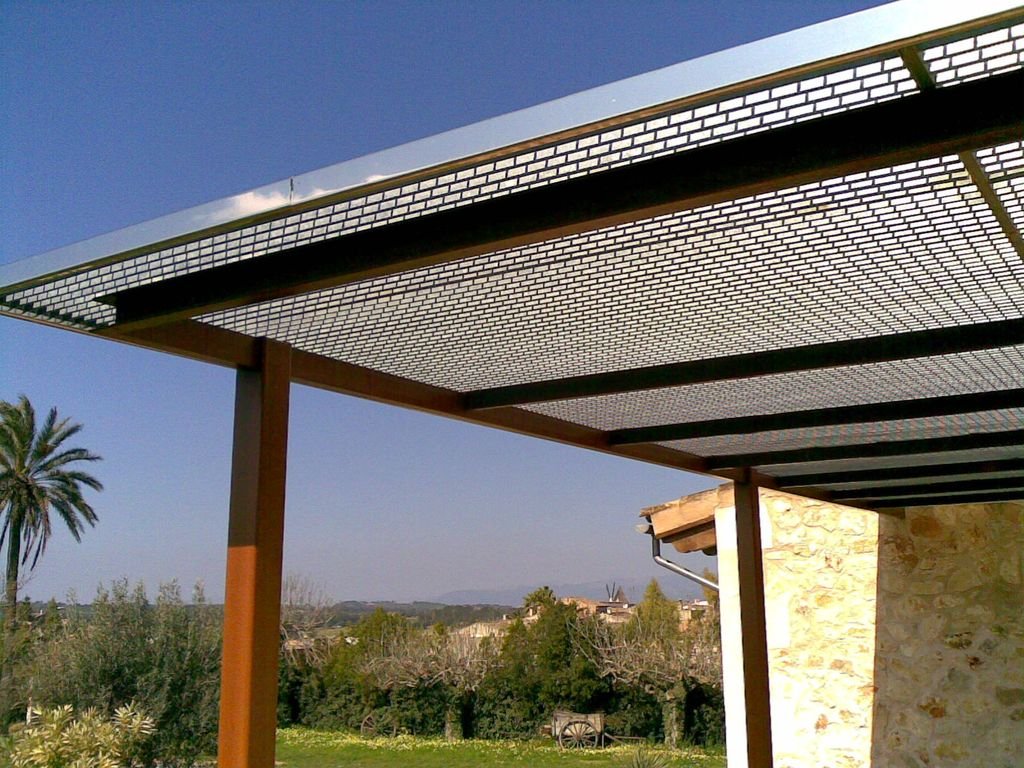 Vista de un toldo de metal en un patio con árboles y un viento en un día soleado.