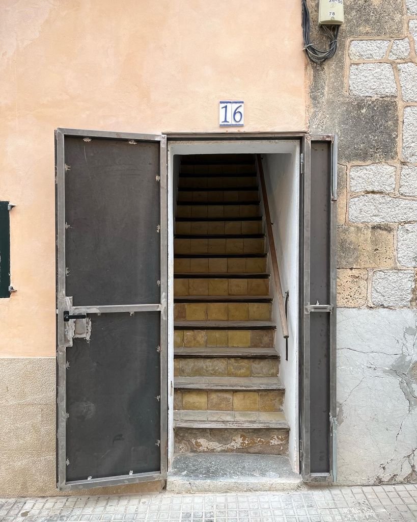 Entrada a una escalera interna con un portal de metal y un número 16 en la pared