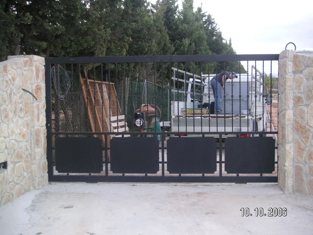 Un hombre trabajando en la plataforma de una puerta para autos con herramientas y materiales de construcción.